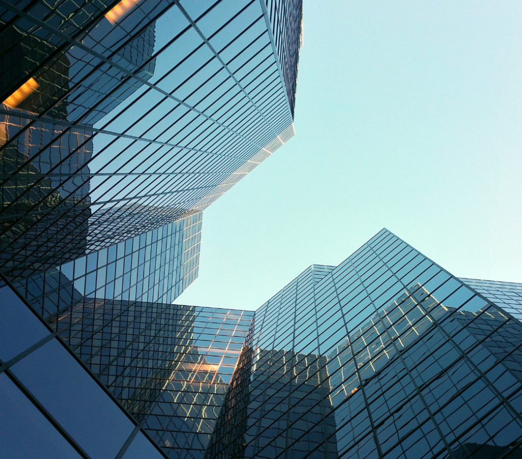 Upward view of modern glass skyscrapers with reflective surfaces and clear blue sky in the background.